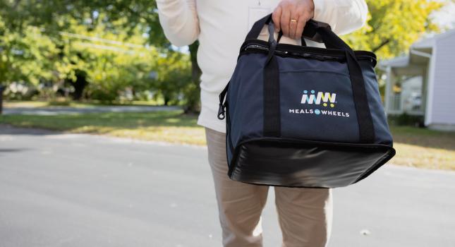 volunteer carrying a meal delivery bag