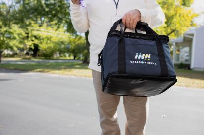 volunteer carrying a meal delivery bag